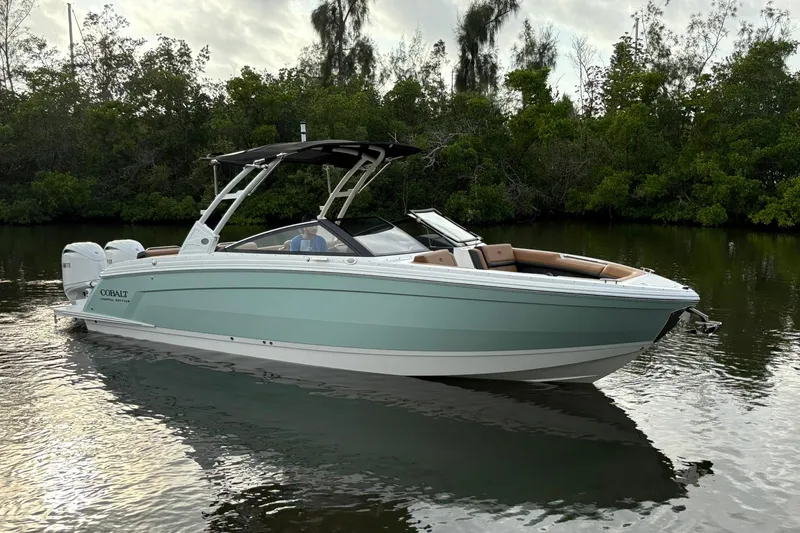 The Image of 2026 Cobalt R8 Outboard boat on calm water, surrounded by lush greenery. - 0