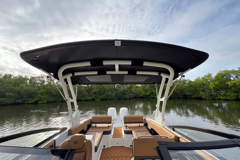 Slide: The Image of 2026 Cobalt R8 Outboard boat with canopy, on calm water, surrounded by trees. - 20