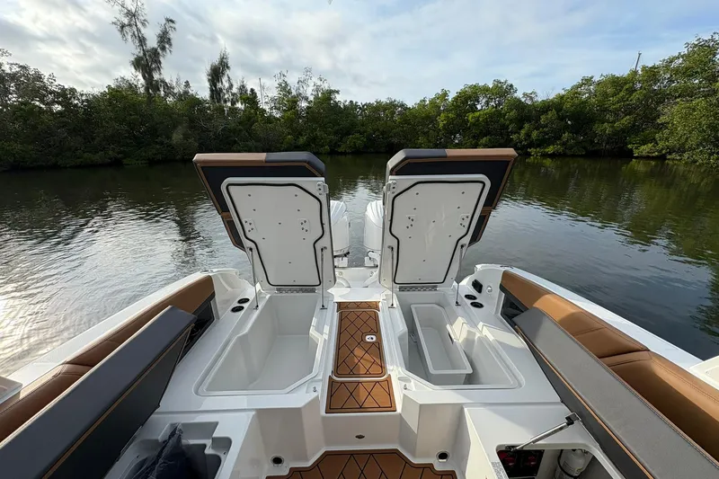 Slide: The Image of 2026 Cobalt R8 Outboard boat with open storage compartments, docked by lush greenery. - 22