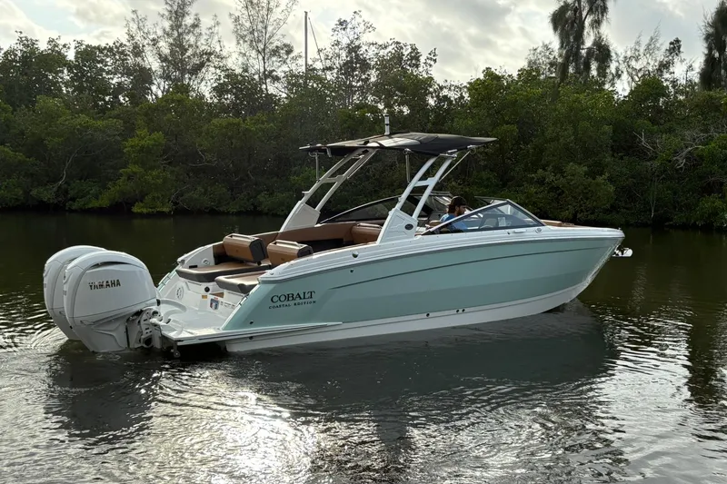 Slide: The Image of 2026 Cobalt R8 Outboard boat on calm water, surrounded by lush greenery. - 6
