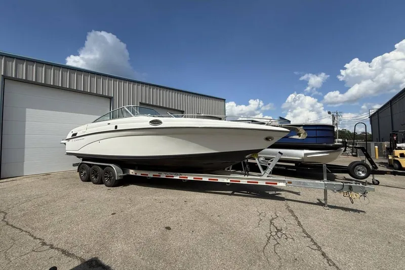 Slide: The Image of 2005 Crownline 288 BR boat on trailer, parked outside industrial building under blue sky. - 27