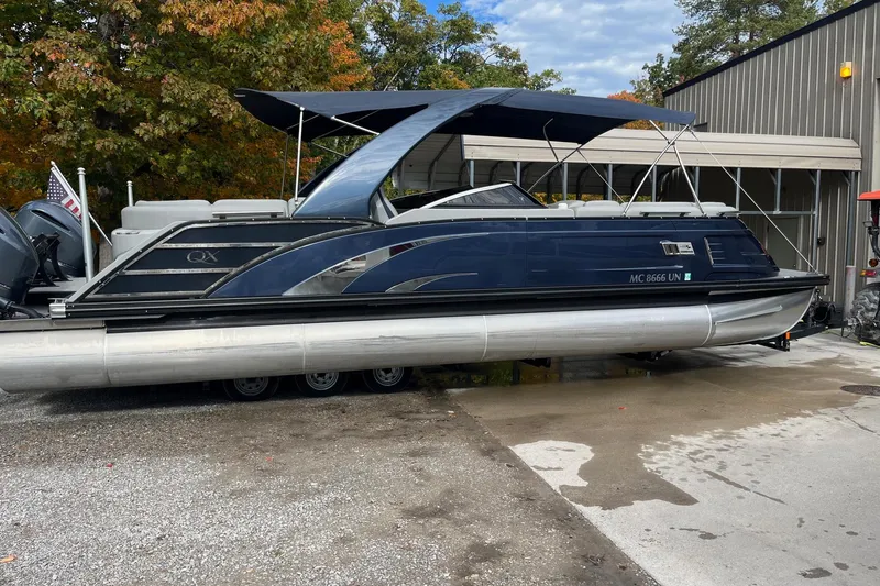 The Image of 2021 Bennington 27 QXFBWAX2 pontoon boat with canopy, parked near a building. - 1