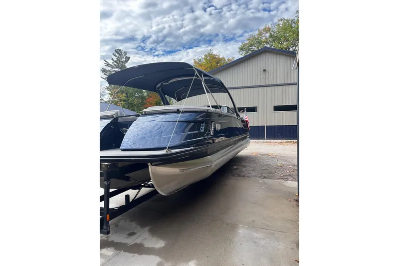 Slide: The Image of 2021 Bennington 27 QXFBWAX2 pontoon boat with canopy, parked near a building. - 19