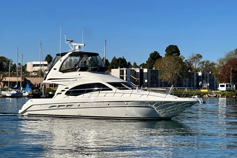 Slide: The Image of 2005 Sea Ray 420 Sedan Bridge yacht cruising on calm waters near a marina. - 2