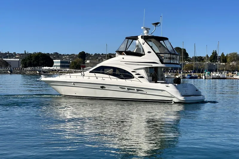 Slide: The Image of 2005 Sea Ray 420 Sedan Bridge yacht cruising on calm waters under clear blue sky. - 3
