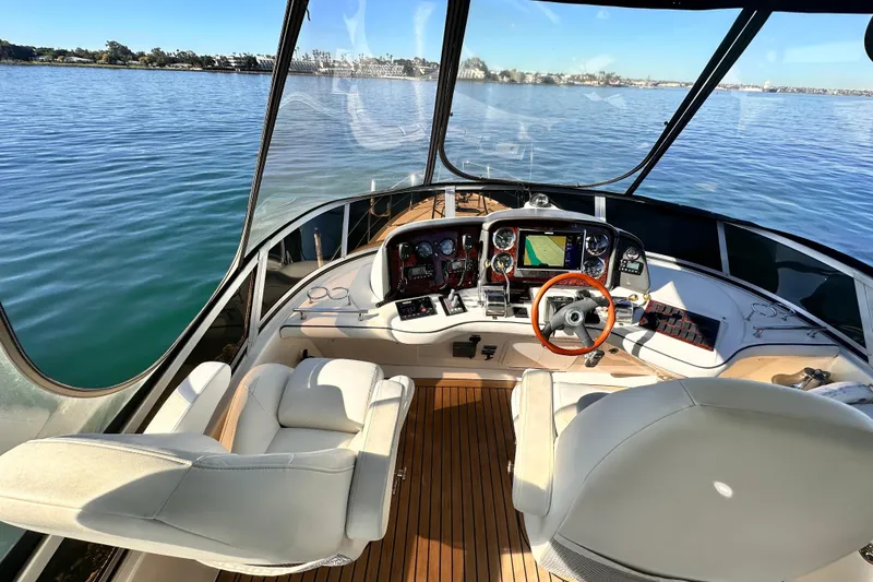 Slide: The Image of 2005 Sea Ray 420 Sedan Bridge helm with luxurious seating and navigation controls on calm waters. - 8