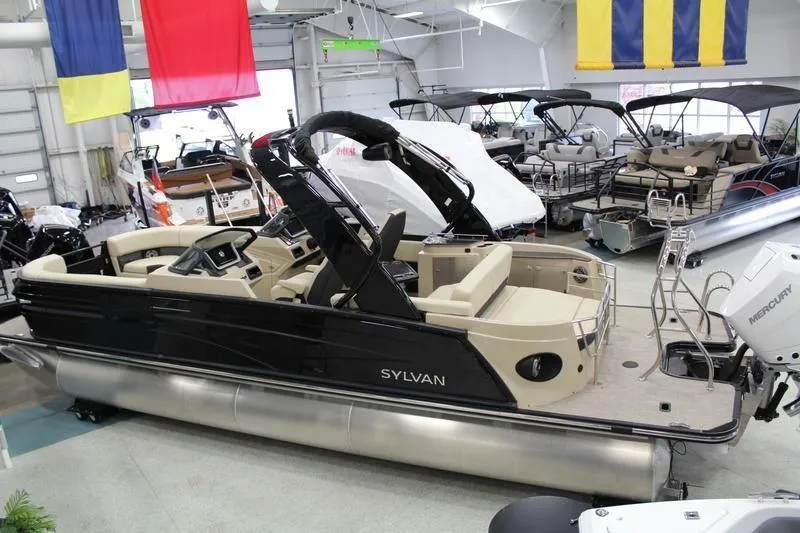 Slide: The Image of 2024 Sylvan G5 CLZ DC pontoon boat displayed in a showroom with colorful flags. - 4