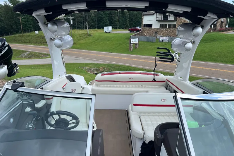 Slide: The Image of 2018 Cobalt R5 Surf boat interior with white seating and speakers, parked near a road. - 22