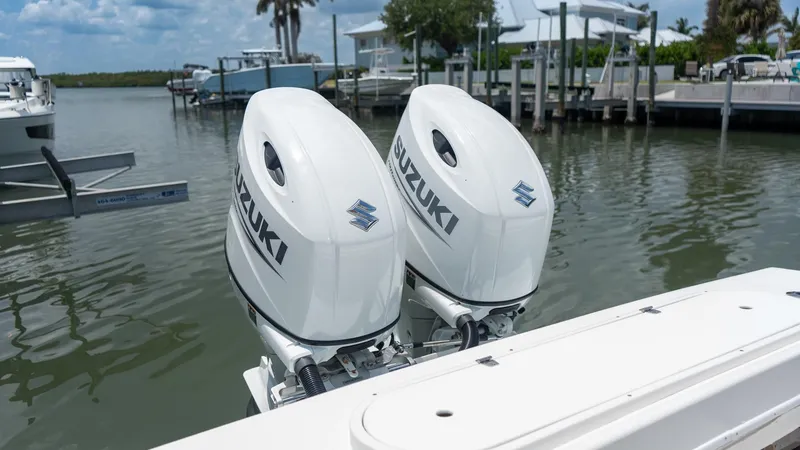 Slide: The Image of Twin Suzuki outboard motors on a 2021 C-Hawk 29CC boat docked by the water. - 8