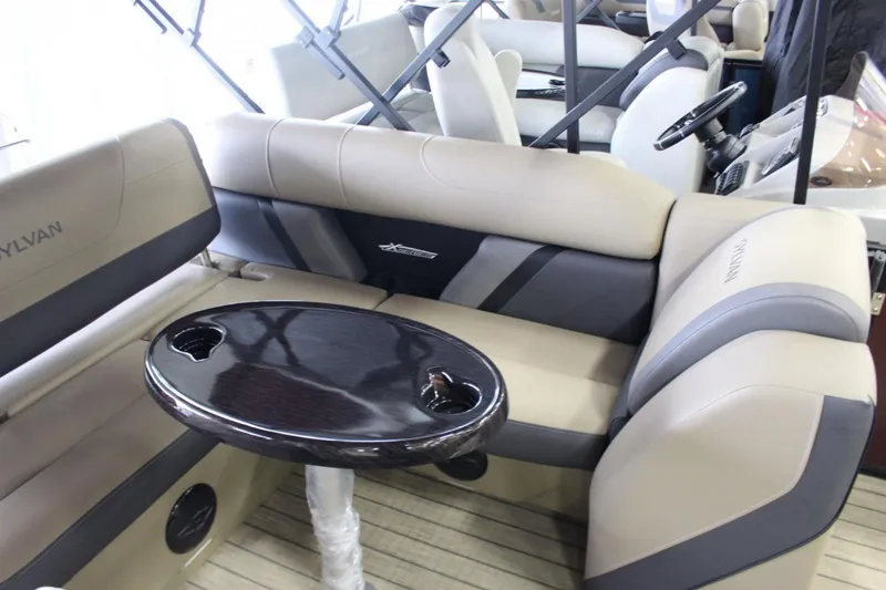 Slide: The Image of 2024 Sylvan Mirage X X3 boat interior with beige seating and dark wood table. - 7