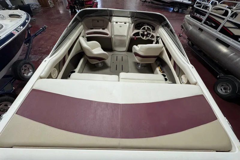 Slide: The Image of 2000 Bryant 214 Walk Through boat interior with maroon and beige seating, steering wheel, and dashboard. - 4