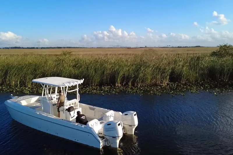 Slide: The Image of Sea Cat SL5 Cat 1997 boat cruising in a serene waterway with grassy banks. - 12