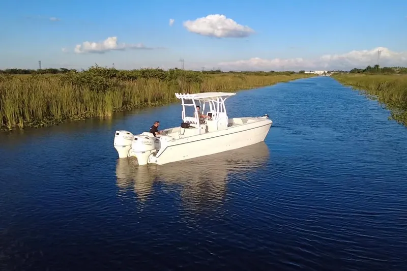 Slide: The Image of 1997 Sea Cat SL5 Cat boat cruising on a serene river under a clear blue sky. - 15