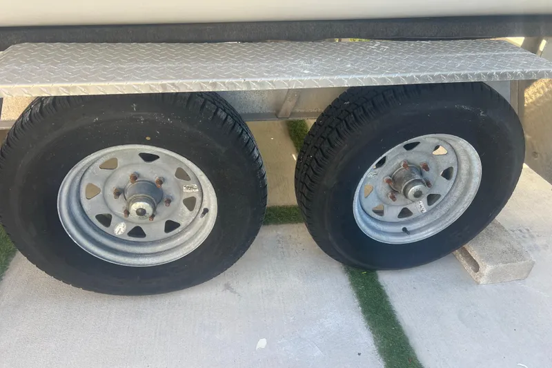 Slide: The Image of Trailer wheels of a 1997 Sea Cat SL5 Cat boat on concrete surface. - 36