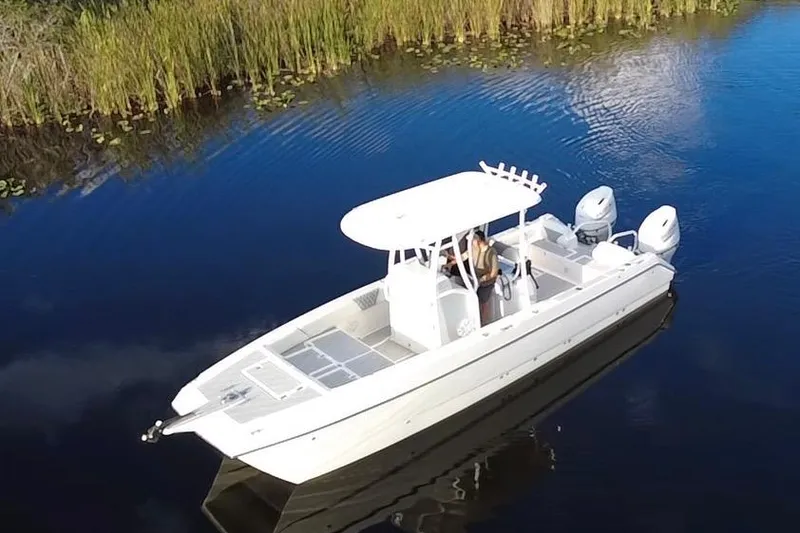 The Image of 1997 Sea Cat SL5 Cat boat on calm water, surrounded by reeds. - 0