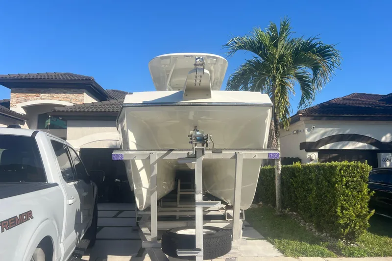 Slide: The Image of 1997 Sea Cat SL5 Cat boat on trailer, parked beside a white truck, with palm tree background. - 30