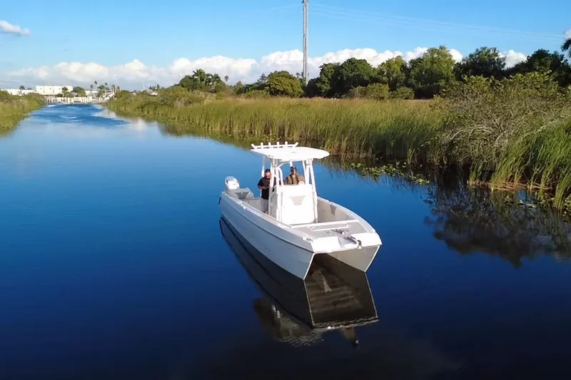Slide: The Image of 1997 Sea Cat SL5 Cat boat cruising on a serene river, surrounded by lush greenery. - 4
