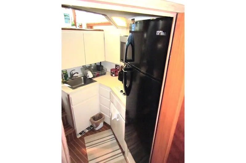 Slide: The Image of Compact kitchen in 1992 Hatteras 40 Motor Yacht with black fridge and white cabinets. - 15