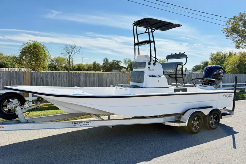 The Image of 2026 Shallow Sport 24 Sport boat on trailer, parked outdoors under clear sky. - 1