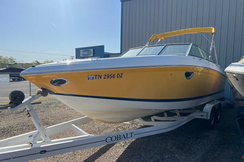 Slide: The Image of 2008 Cobalt 252 boat with yellow hull on trailer, parked outdoors. - 1