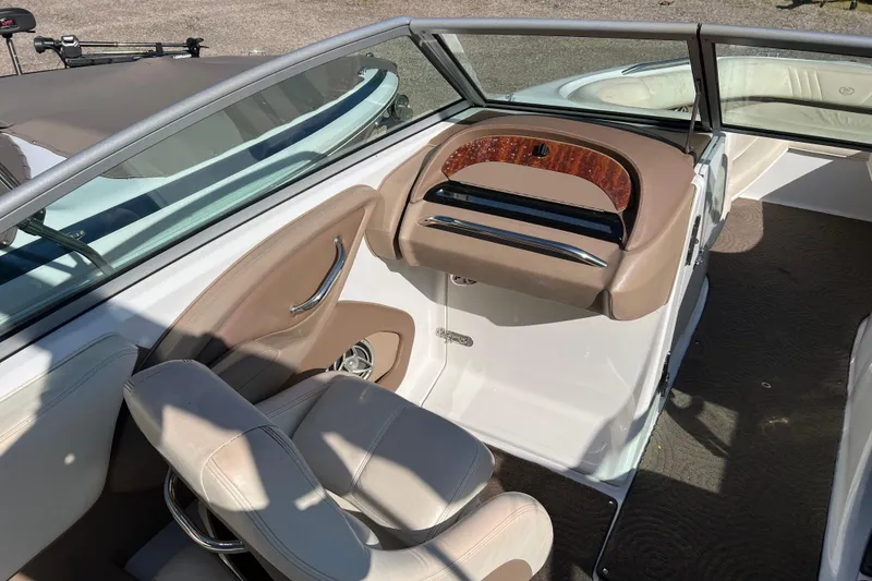 Slide: The Image of 2008 Cobalt 252 boat interior with beige seating and wood-accented dashboard. - 10