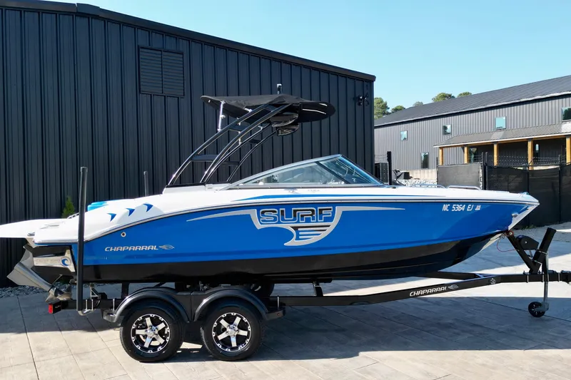The Image of 2019 Chaparral 21 H2O Surf boat in blue on trailer, parked outdoors. - 0