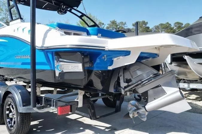 Slide: The Image of 2019 Chaparral 21 H2O Surf boat with vibrant blue and white design on trailer. - 10
