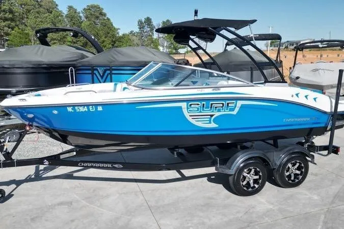 Slide: The Image of 2019 Chaparral 21 H2O Surf boat with blue and white seating, docked outdoors. - 15