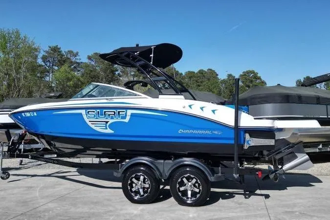 Slide: The Image of 2019 Chaparral 21 H2O Surf boat with blue and white design on a trailer. - 16