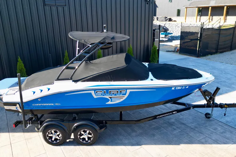 Slide: The Image of 2019 Chaparral 21 H2O Surf boat on trailer, blue and white design, parked outdoors. - 20