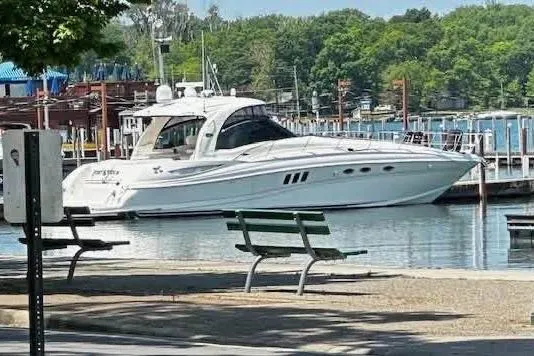 The Image of 2006 Sea Ray 52 Sundancer yacht docked at a marina with lush green surroundings. - 0