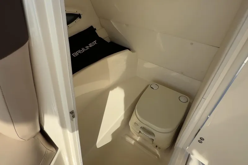Slide: The Image of 2015 Bayliner 210 Deck Boat interior with portable toilet and Bayliner cushion. - 13