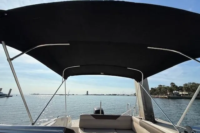 Slide: The Image of 2015 Bayliner 210 Deck Boat with canopy on calm water, scenic view. - 19