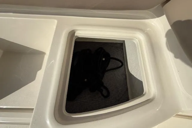 Slide: The Image of Storage compartment on a 2015 Bayliner 210 Deck Boat with coiled rope inside. - 24