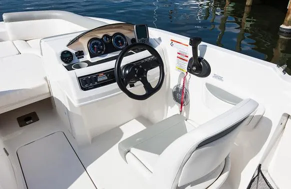Slide: The Image of 2015 Bayliner 210 Deck Boat docked on calm water, featuring a sleek design and canopy. - 5