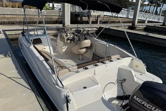 Slide: The Image of 2015 Bayliner 210 Deck Boat docked, featuring spacious seating and a Mercury outboard motor. - 9
