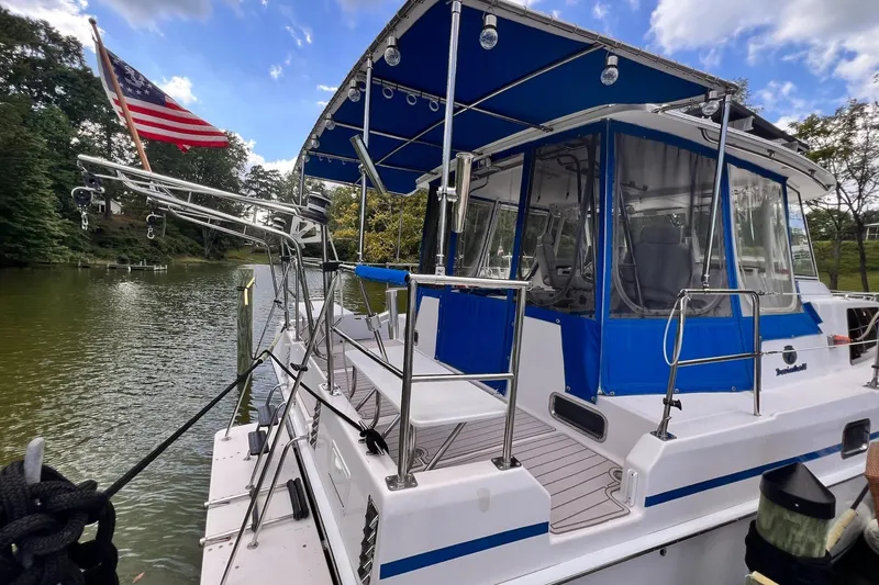 Slide: The Image of 2002 Endeavour Trawlercat 36 docked, featuring blue canopy and American flag. - 12