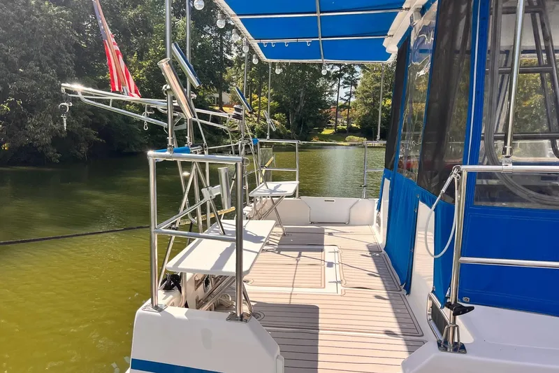 Slide: The Image of 2002 Endeavour Trawlercat 36 on calm water, featuring spacious deck and blue canopy. - 13