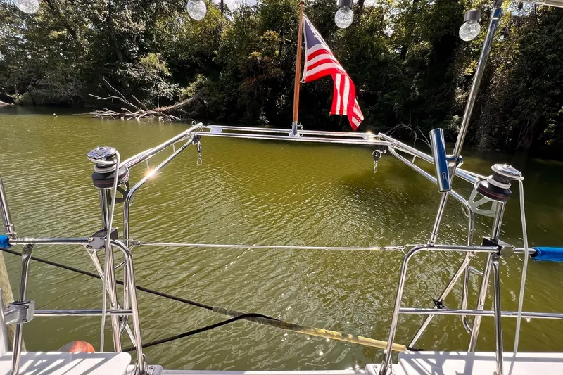 Slide: The Image of 2002 Endeavour Trawlercat 36 on calm water with American flag, surrounded by trees. - 14