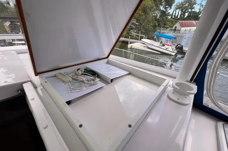 Slide: The Image of Open storage compartment on 2002 Endeavour Trawlercat 36, with manuals and accessories, docked by water. - 24