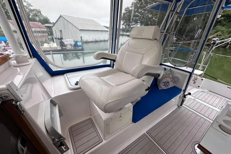 Slide: The Image of Captain's chair on 2002 Endeavour Trawlercat 36, overlooking serene marina with boathouse. - 28