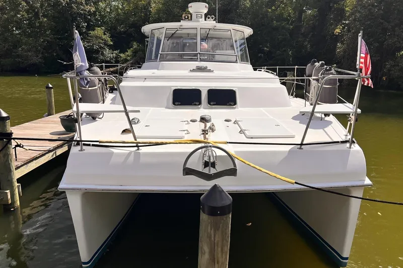 Slide: The Image of 2002 Endeavour Trawlercat 36 docked, front view with American flag, lush greenery background. - 4