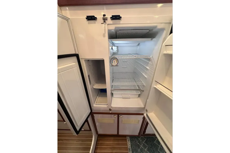 Slide: The Image of Open refrigerator inside 2002 Endeavour Trawlercat 36, featuring wire shelves and a thermometer. - 47