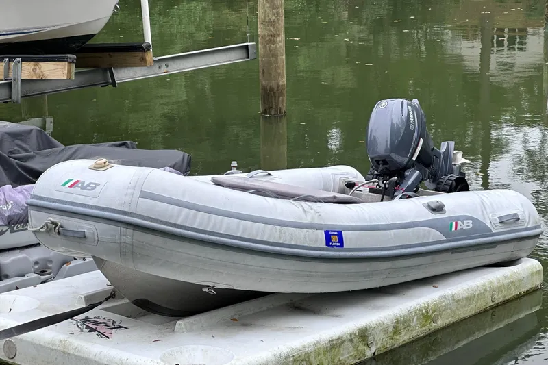 Slide: The Image of Inflatable boat with Yamaha motor docked on water, near Endeavour Trawlercat 36, 2002 model. - 56