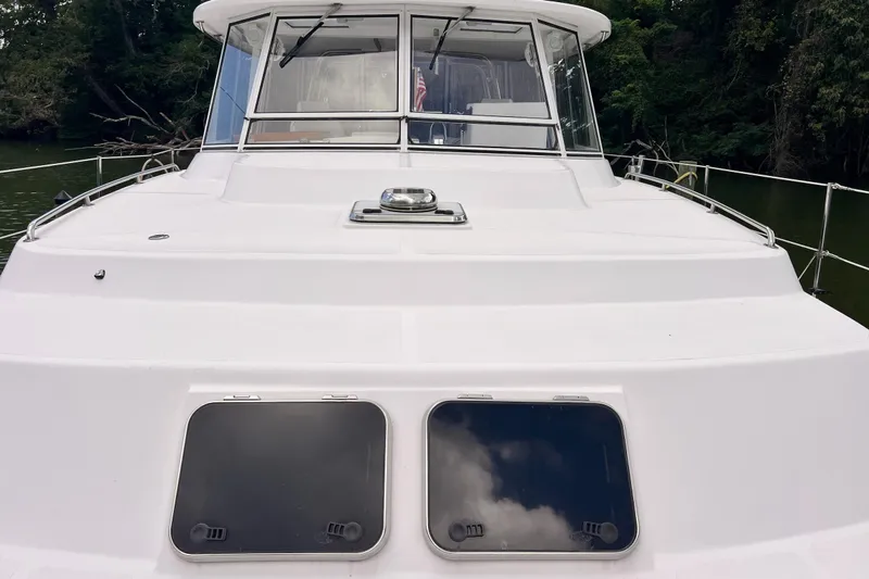 Slide: The Image of 2002 Endeavour Trawlercat 36 boat deck with windows, surrounded by lush greenery. - 6