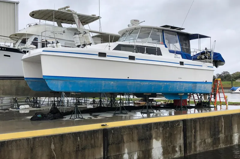Slide: The Image of 2002 Endeavour Trawlercat 36 on dry dock, white and blue hull, marina background. - 61
