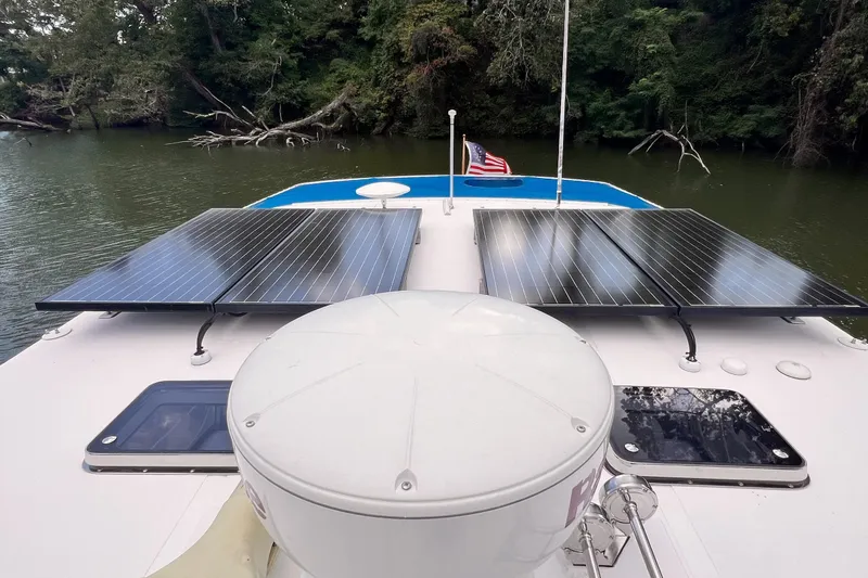 Slide: The Image of 2002 Endeavour Trawlercat 36 with solar panels on deck, cruising in a serene river setting. - 9