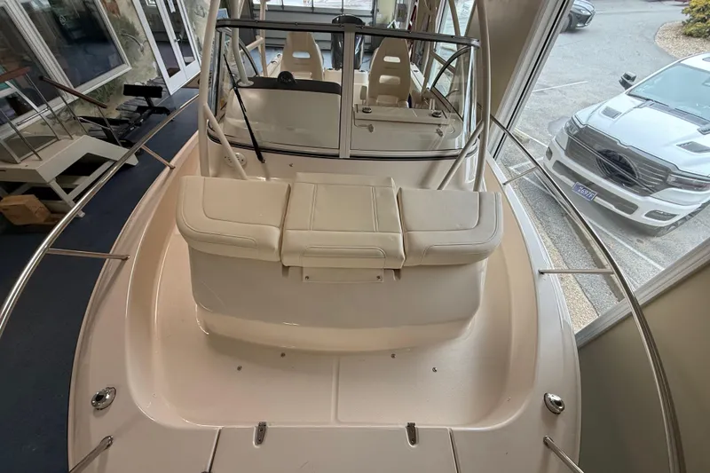 Slide: The Image of 2026 Grady-White Adventure 218 boat interior, showcasing seating and helm area in showroom. - 11