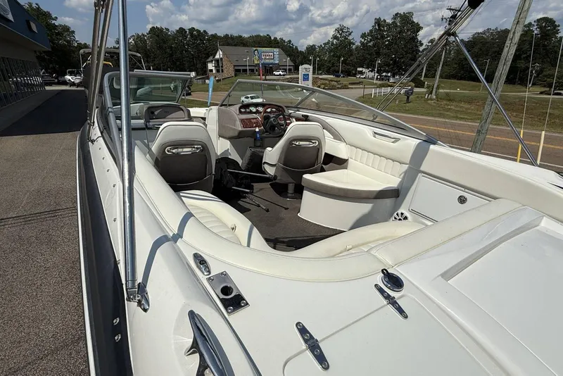 Slide: The Image of 2005 Cobalt 240 boat interior with white seating and dashboard, parked outdoors. - 12