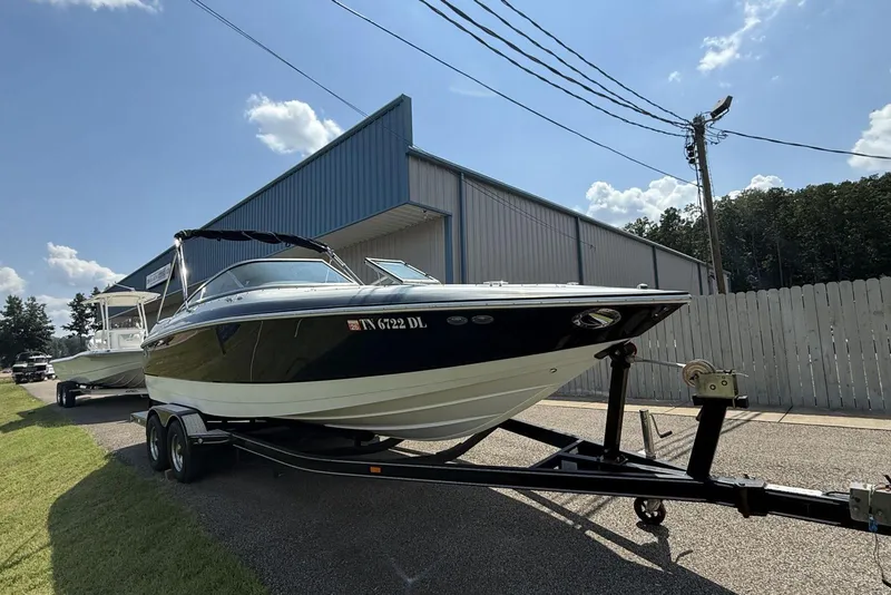 Slide: The Image of 2005 Cobalt 240 boat on trailer near a blue warehouse under a clear sky. - 3